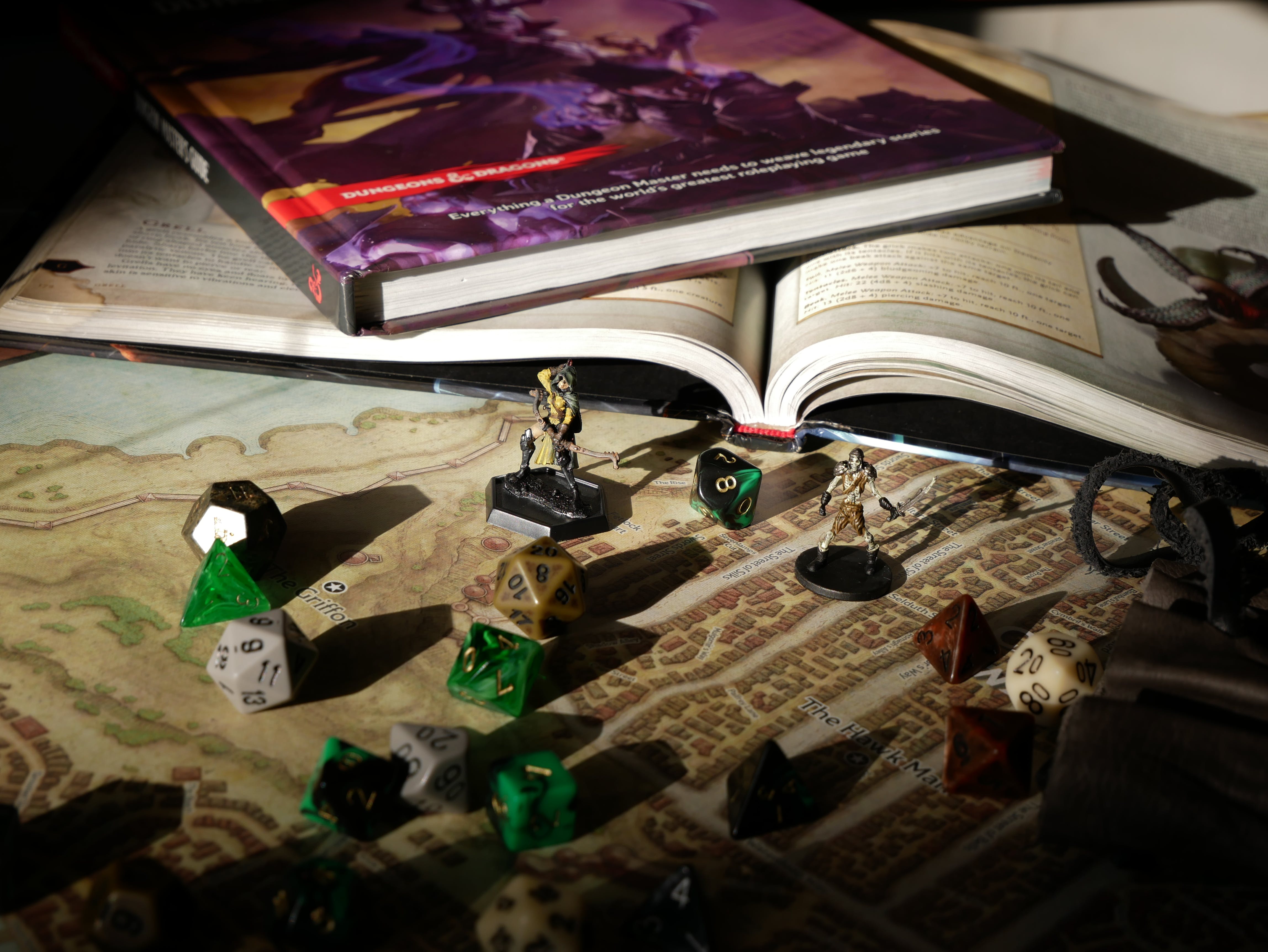 A number of dice on a city map next to a couple of RPG books